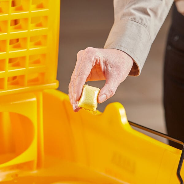 A hand holding a yellow packet of Noble Chemical QuikPacks.