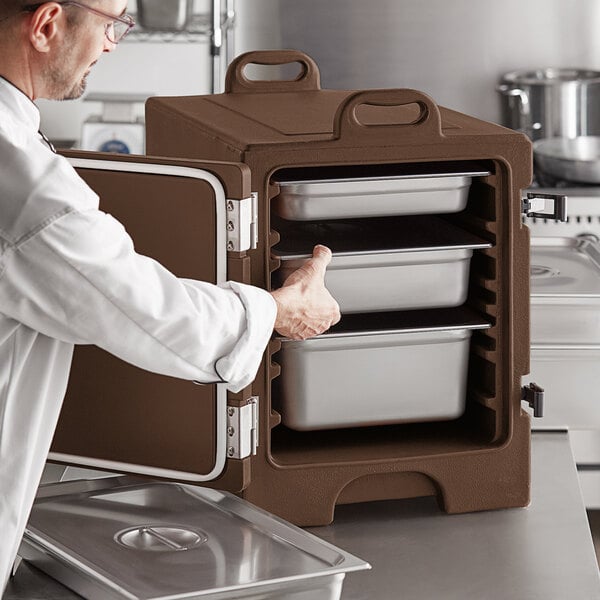 A man opening a brown CaterGator metal food pan carrier.