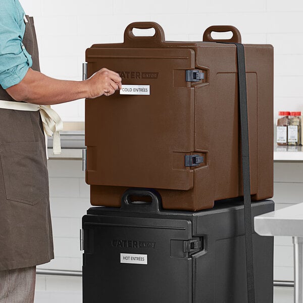 A man standing next to a brown CaterGator food pan carrier.