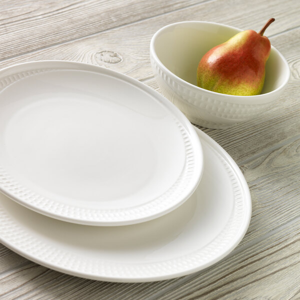 A white Libbey porcelain platter next to a bowl with a pear in it.