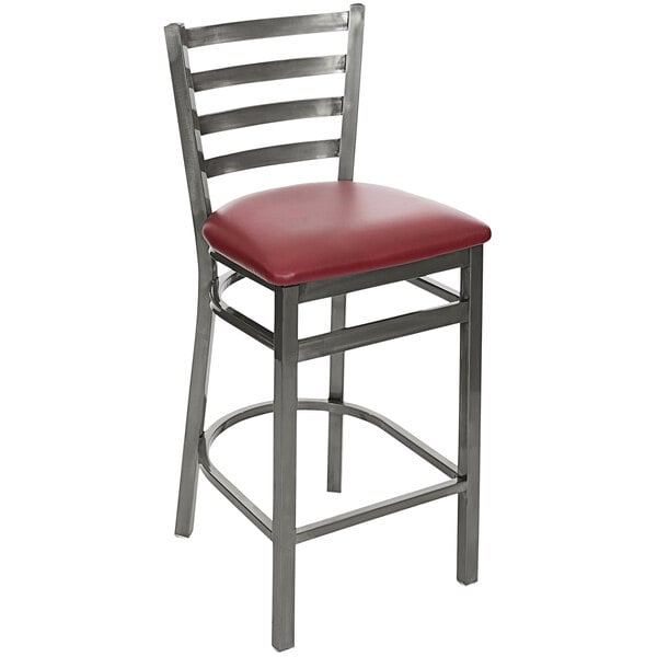 A BFM Seating metal counter height bar stool with a burgundy cushion.