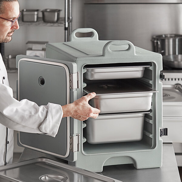 A man in a white coat opening a CaterGator slate blue front loading metal food container.