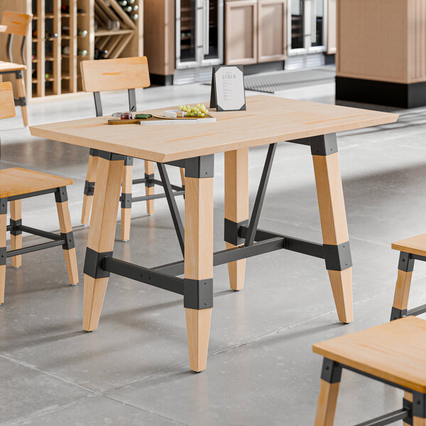 A standard height trestle table with a bleached oak finish and metal supports, designed for 30" x 48" table tops.
