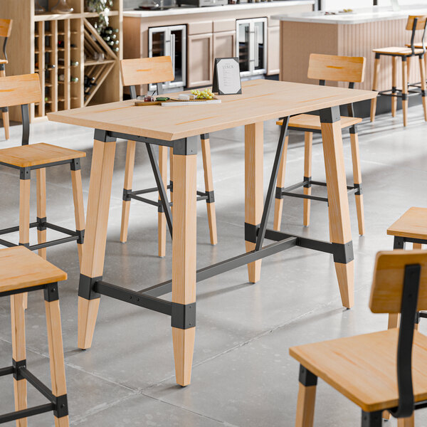 A bar height trestle table with a bleached oak finish and black metal accents, designed for 30" x 60" table tops.