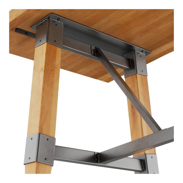 A wooden trestle table base with metal supports and a honey maple finish, designed for 30" x 72" table tops.
