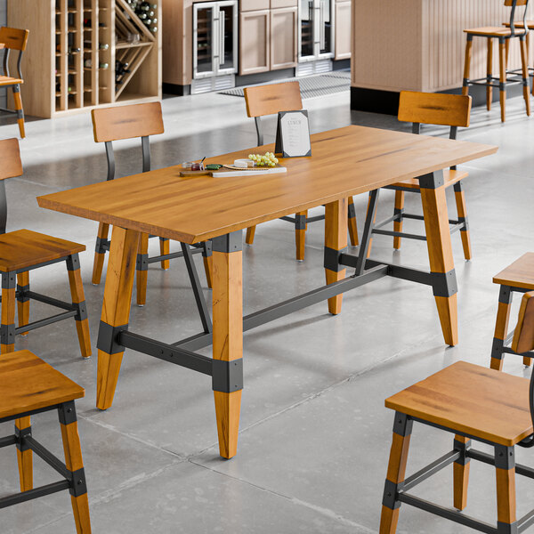 A standard height trestle table with a honey maple finish and industrial metal accents, designed for 30" x 72" table tops.