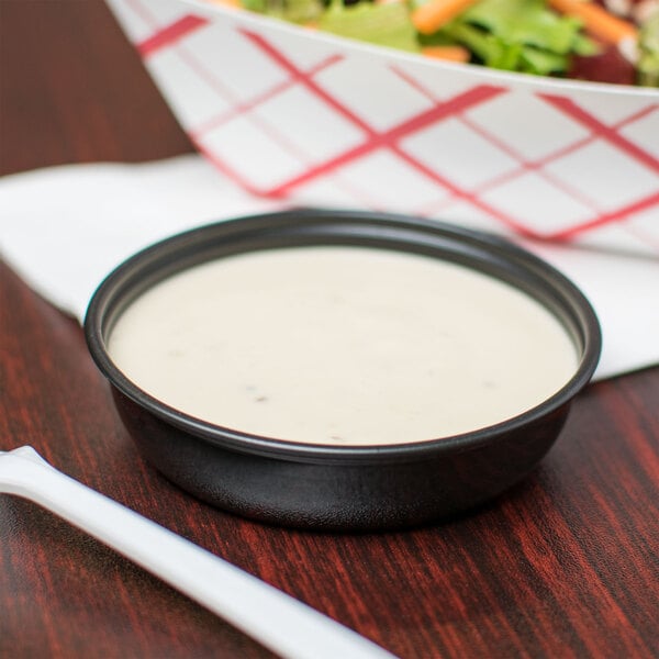 A bowl of salad with Solo black wide sauce next to it.