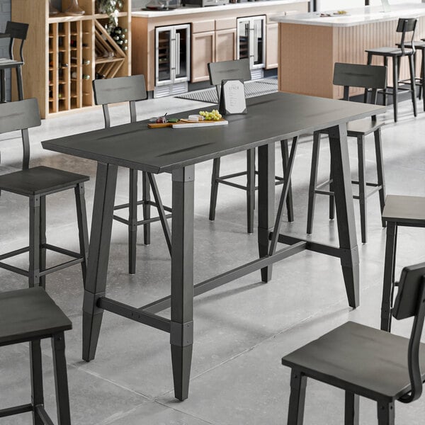 A slate gray industrial-style bar height trestle table with matching chairs, designed for 30" x 72" table tops.
