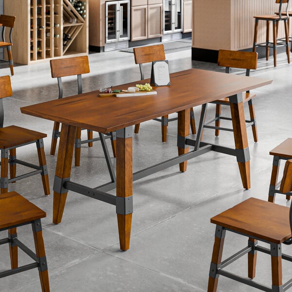 A standard height trestle table with a rustic walnut finish and industrial metal accents, designed for 30" x 72" table tops.