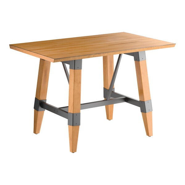 A rectangular wooden table with a honey maple finish, featuring angled legs reinforced with gray metal brackets and supports.