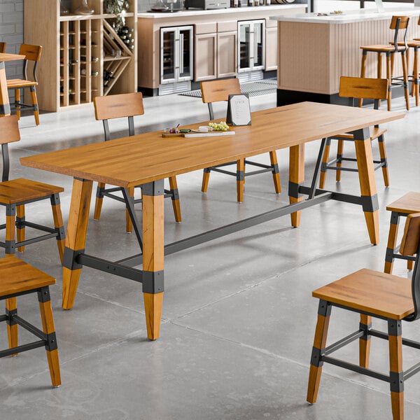 A rectangular solid wood trestle base table with a honey maple finish in an industrial style dining area.