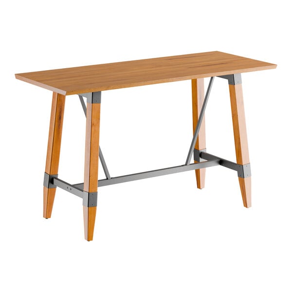 A rectangular bar height table with a solid wood live edge top in a honey maple finish and an industrial-style trestle base.