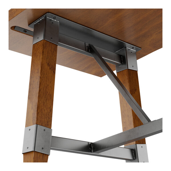 A close-up view of the metal trestle base and wooden legs of a rectangular table with a rustic walnut finish.