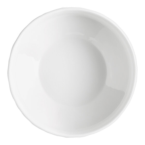 A plain white, round porcelain bowl with a slightly wavy rim, viewed from above.