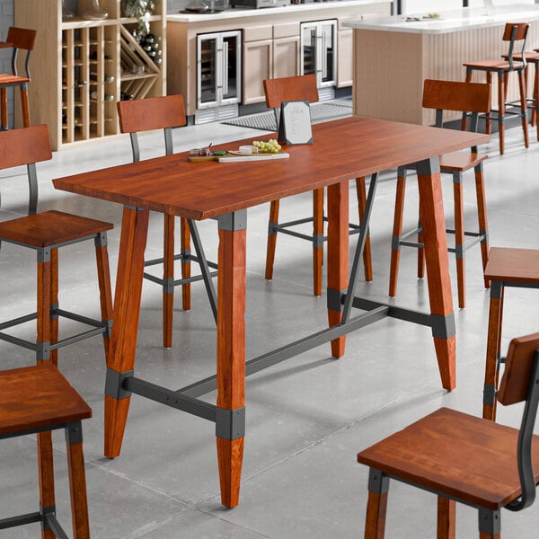 A Lancaster Table & Seating live edge wood bar height table with chairs and a plate of food on it.