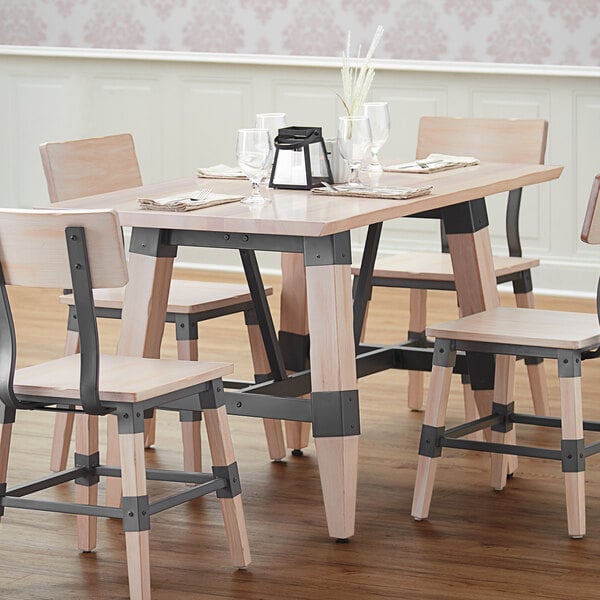 A Lancaster Table & Seating solid wood live edge dining table with a white wash finish on a table in a restaurant dining area.