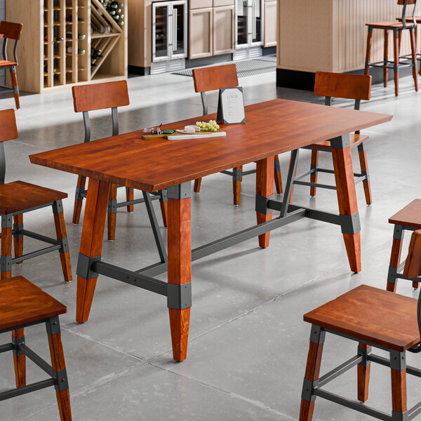 A rectangular solid wood live edge table with a rustic mahogany finish and a trestle base, surrounded by matching chairs in a modern dining setting.