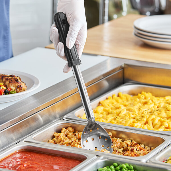 A person in gloves holding an American Metalcraft stainless steel perforated spoon over food.