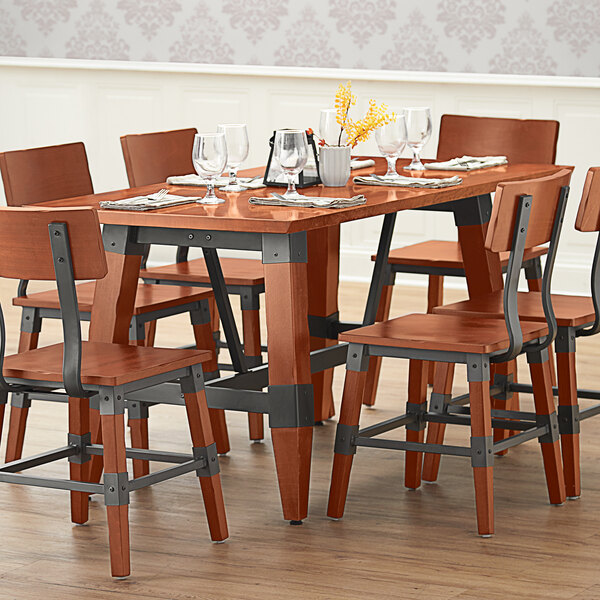 A Lancaster Table & Seating wooden table with wine glasses and chairs.