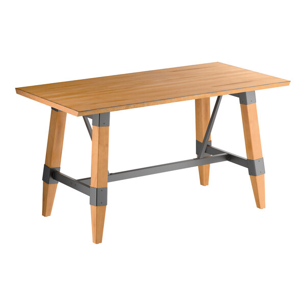 A rectangular wooden table with a honey maple finish, featuring angled legs and metal supports for an industrial look.