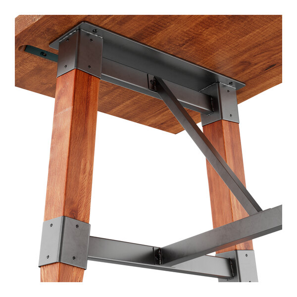 A bar height trestle base table with a solid wood live edge top and rustic mahogany finish, featuring metal supports and accents.