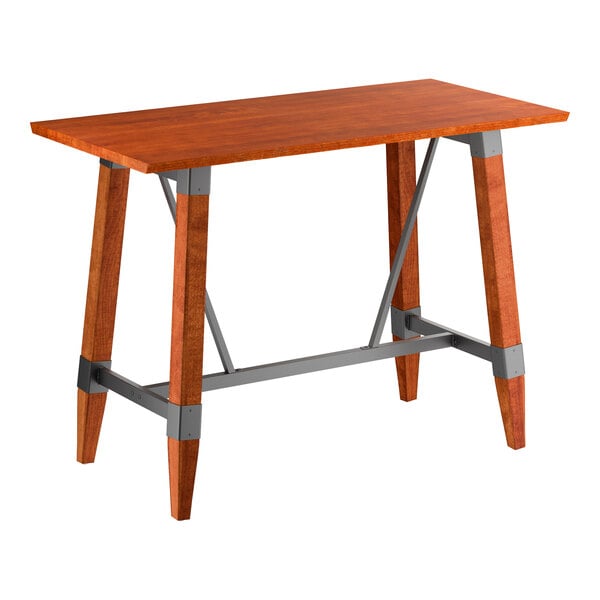 A rectangular bar-height table with a solid wood top and legs in a warm mahogany finish, featuring gray metal support brackets and crossbars for added stability.