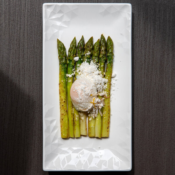 A white rectangular porcelain platter with asparagus and a poached egg.