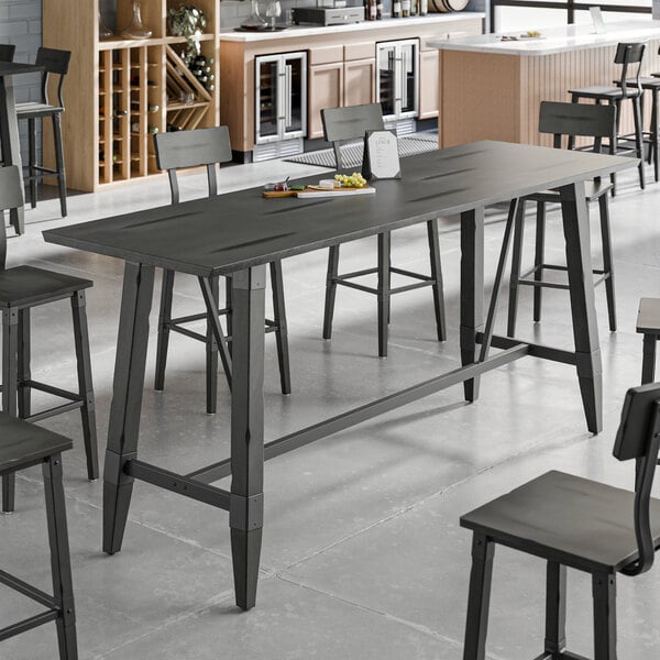 A Lancaster Table & Seating live edge wood bar height trestle table with chairs and a book on it.