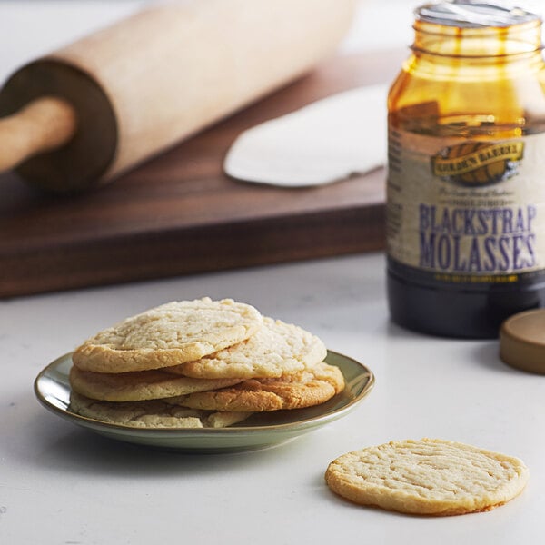 A plate of cookies and a jar of Golden Barrel black strap molasses on a table.