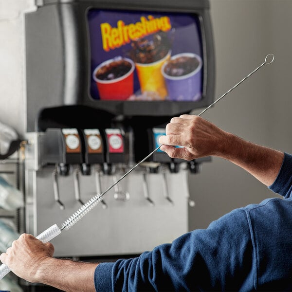 A man using a Carlisle Sparta Spectrum pipe brush to clean a straw.