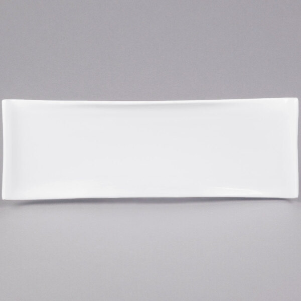 A white rectangular porcelain serving platter with a curved edge on a gray background.