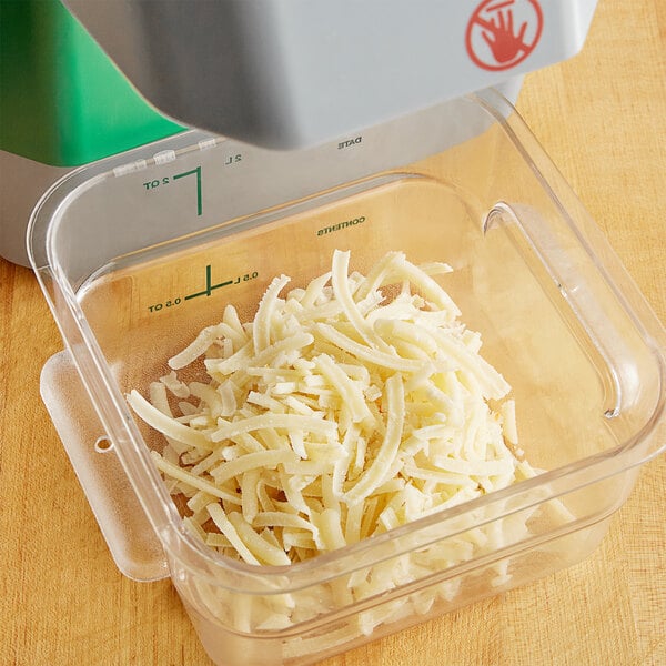 A close-up of a grey AvaMix Revolution grating and shredding disc for a food processor with shredded cheese on it.