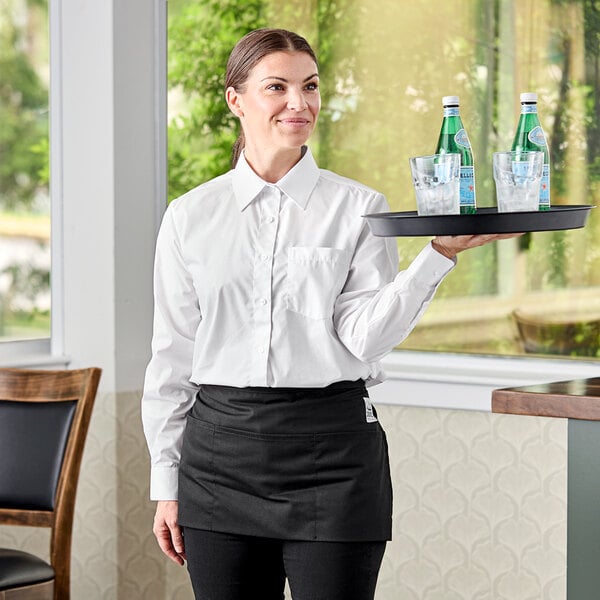 A woman in a Henry Segal white dress shirt holding a tray with glasses and a bottle of water.