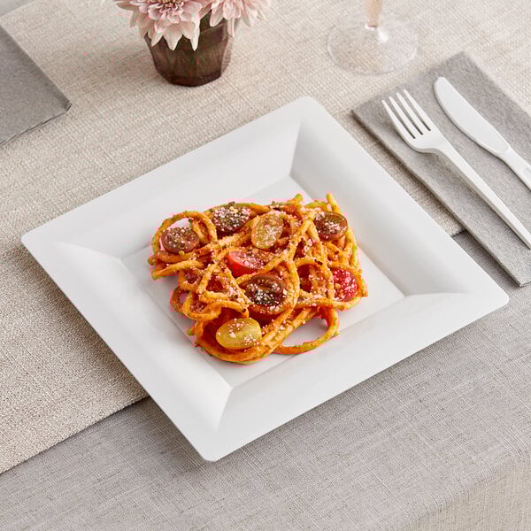 A WNA Comet white plastic dinner plate with spaghetti and meatballs on it on a table.