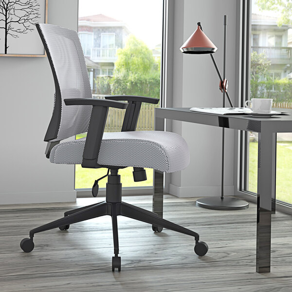 A Boss gray mesh task chair next to a desk.