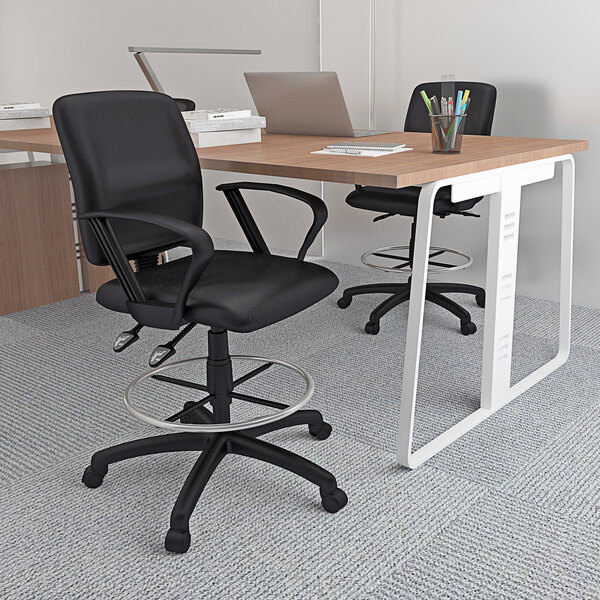 A black Boss drafting stool with loop arms at a desk with a laptop and a cup of pens.