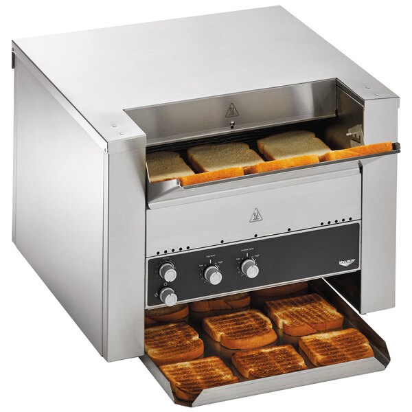 A Vollrath convertible conveyor toaster with bread inside and toasted bread on a conveyor belt.