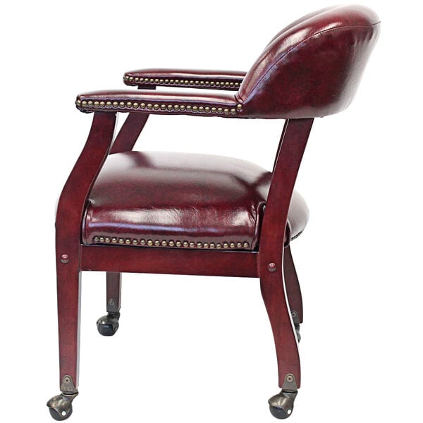 A Boss burgundy vinyl captain's chair with wheels and studded arms.