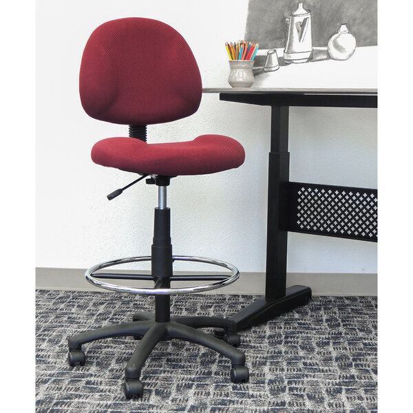 A Boss burgundy drafting stool with footring on a metal base.