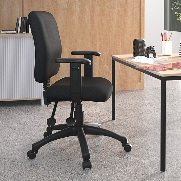 A black Boss office chair with adjustable arms at a desk with a laptop.