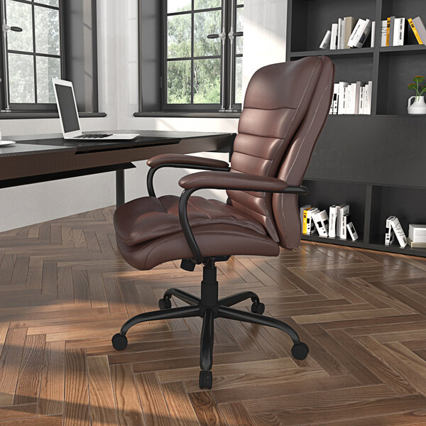 A Boss brown leather office chair at a desk with a laptop and bookshelf.