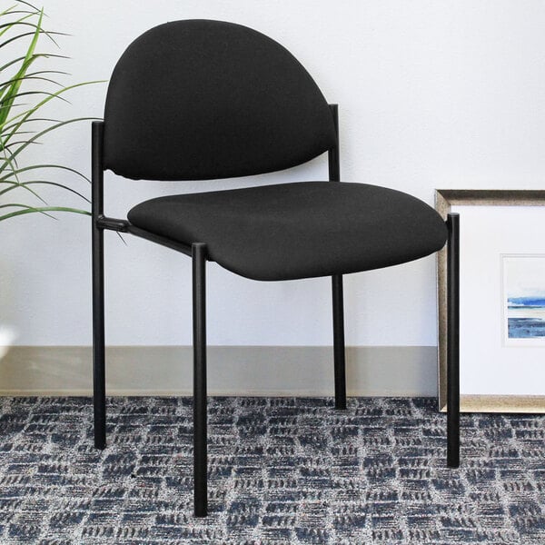 A Boss black stacking chair next to a plant.