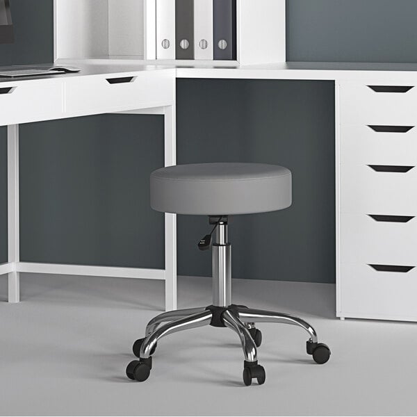 A gray Boss Office adjustable stool under a white desk.