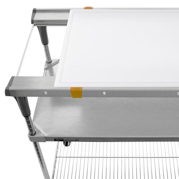 A white cutting board on a metal shelf with a metal frame.
