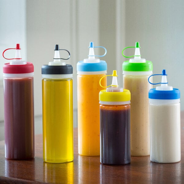 A group of Tablecraft red squeeze bottles on a counter.