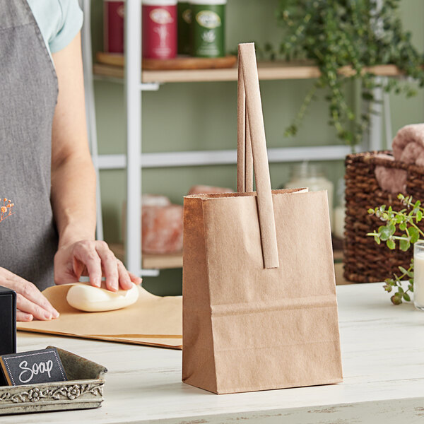 A woman's arm and hand using a Choice brown paper bag on a counter.