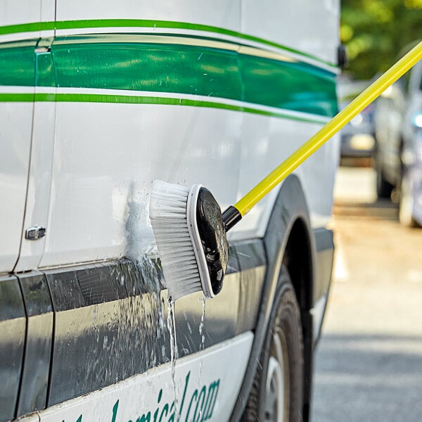 A person using a Carlisle Flo-Pac vehicle brush to clean a car.