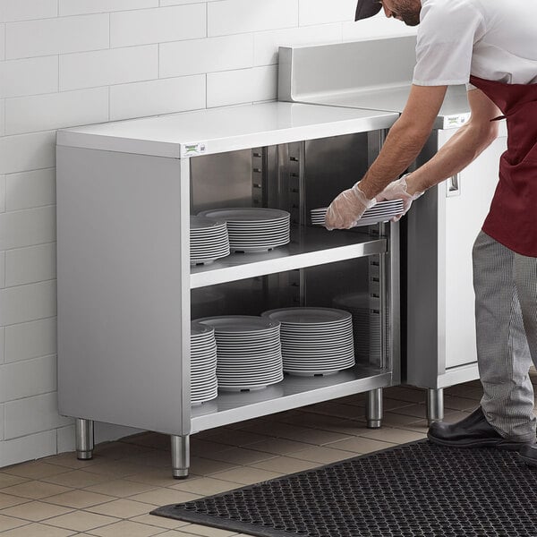 a person holding plates in a cabinet