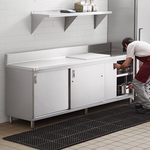 A man working on a Regency stainless steel enclosed base work table in a professional kitchen.