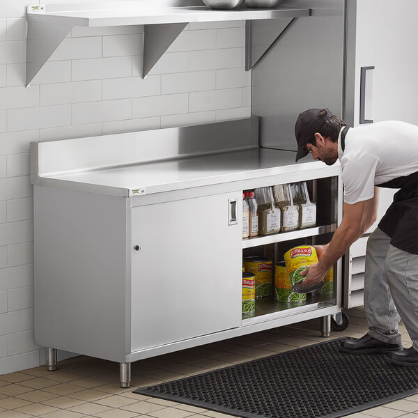 A man opening the sliding doors on a Regency stainless steel enclosed base table.